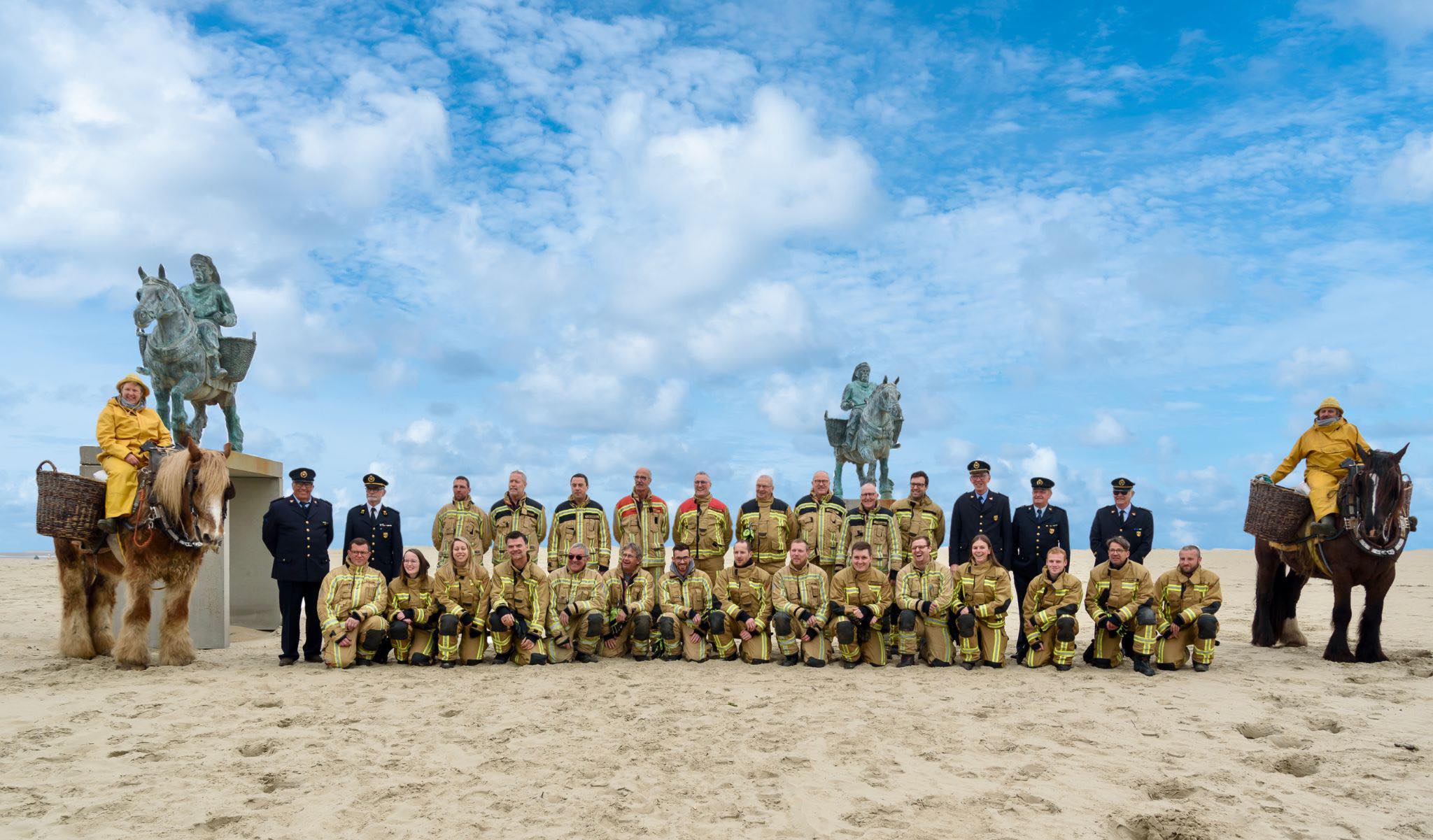 groepsfoto brandweerpost Oostduinkerke op het strand, geflankeerd door peerdenvisschers